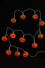 Garland of luminous pumpkins with eyes on a black background - Halloween decoration