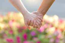 Closeup Of Loving Couple Holding Hands While Walking In The Park