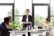 © LIGHTFIELD STUDIOS - multiethnic businesspeople sitting at tables during conference in office