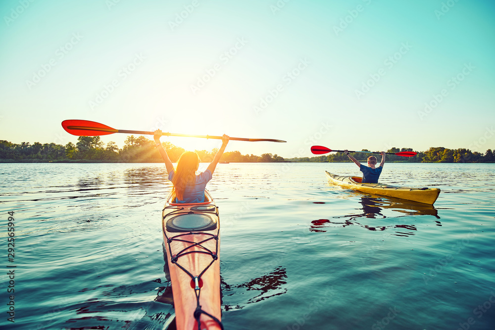 People kayak during sunset in the background. Have fun in your free time. - obrazy, fototapety, plakaty 
