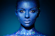 Fashion model woman in blue bright sparkles and neon lights posing in studio. Portrait of beautiful sexy woman. Art design colorful glitter glowing make up