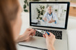 © pressmaster - Sick woman sitting in front of laptop and listening to doctor advice online