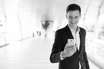 Young handsome businessman using phone outdoors while smiling