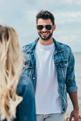 Wall Mural - selective focus of handsome man in denim jacket smiling and looking at woman