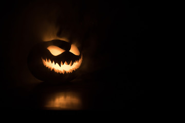 Halloween pumpkin smile and scary eyes for party night. Close up view of scary Halloween pumpkin with eyes glowing inside at black background