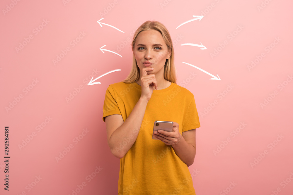 Blonde girl thinks about the right option. Confused and pensive expression. Pink background - obrazy, fototapety, plakaty 
