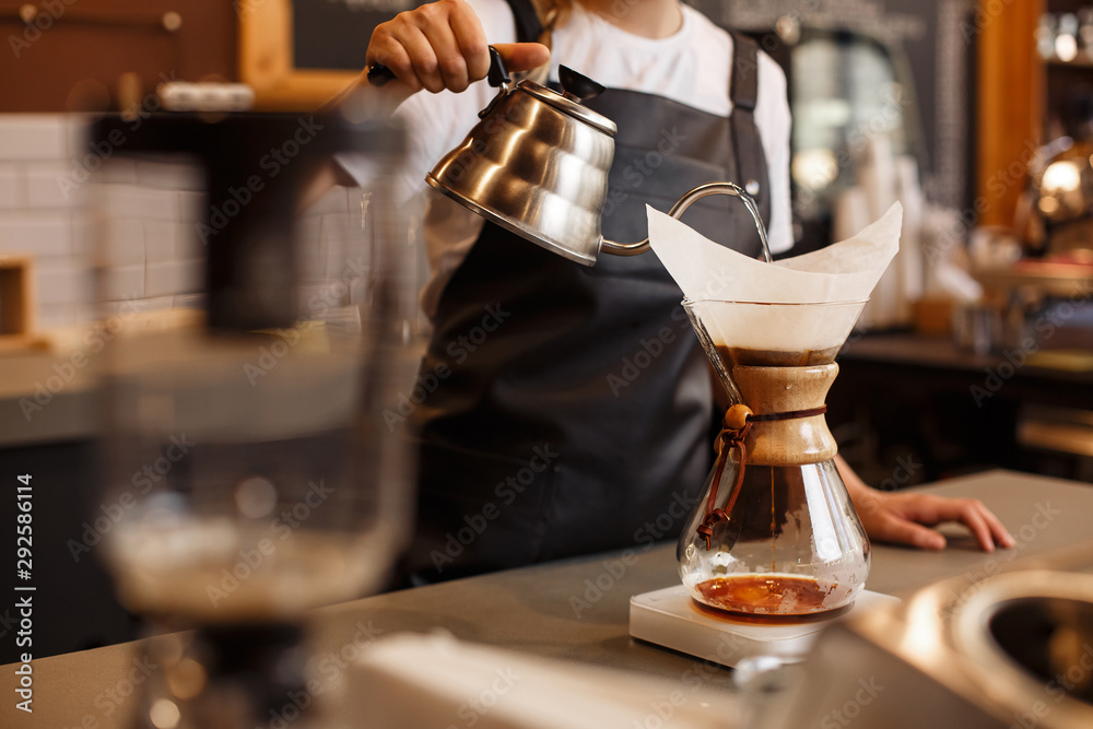 Professional barista preparing coffee using chemex pour over coffee maker and drip kettle. Young woman making coffee. Alternative ways of brewing coffee. Coffee shop concept. - obrazy, fototapety, plakaty 