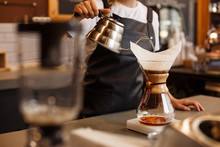 Professional Barista Preparing Coffee Using Chemex Pour Over Coffee Maker And Drip Kettle. Young Woman Making Coffee. Alternative Ways Of Brewing Coffee. Coffee Shop Concept.