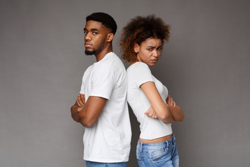 Offended african man and woman standing back to back with crossed hands