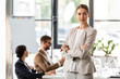 © LIGHTFIELD STUDIOS - attractive businesswoman in formal wear standing with crossed arms in office