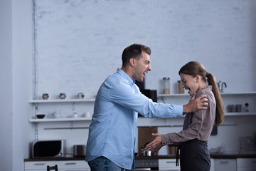 side view of aggressive man in shirt screaming at wife during quarrel
