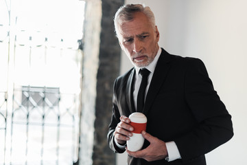 senior man with grey hair holding mortuary urn