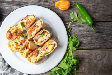 Wall Mural - Mexican egg burritos with fresh sauce on wooden background
