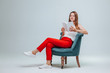 © Smeilov - Girl in red pants sitting in a chair and reading a book with a white cover