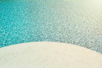 background of water in blue swimming pool, water surface with a sun reflection