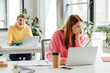 © LIGHTFIELD STUDIOS - pensive girl in glasses using laptop while classmate laughing at her