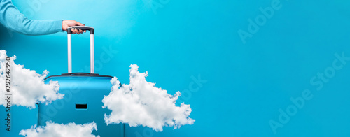 Fotomural blue travel suitcase and clouds over blue background, panoramic mock up image, a