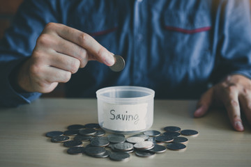 Wall Mural - Men are holding coins dropping to the money box with the concept of saving.