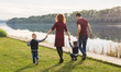 © satura_ - Parenthood and nature concept -Family of mother and father with two boys twins kids in a park at summer by a river at sunny day
