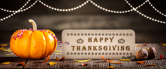 Wall Mural - thanksgiving - mini pumpkin with greeting tag on wooden table decorated with leaves and acorns