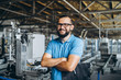 Young engeneer manager with beard checking manufactory, workplace and machinery in big factory.