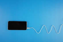 Wave Shape Of White Cable Attached On Smartphone Over Blue Background