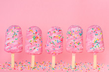 Funny Creative Concept Of Unstable Standing Popsicle Covered And Strewed Sprinkles On Pink Background, Space For Your Greetings