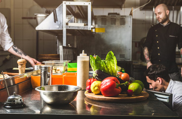 Wall Mural - Professional chef cooking in the kitchen restaurant at the hotel, preparing dinner. A cook in an apron makes a salad of vegetables and pizza.