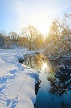 Sunny Winter Scene With River Stream And Sun Shining Through Snow Covered Trees 