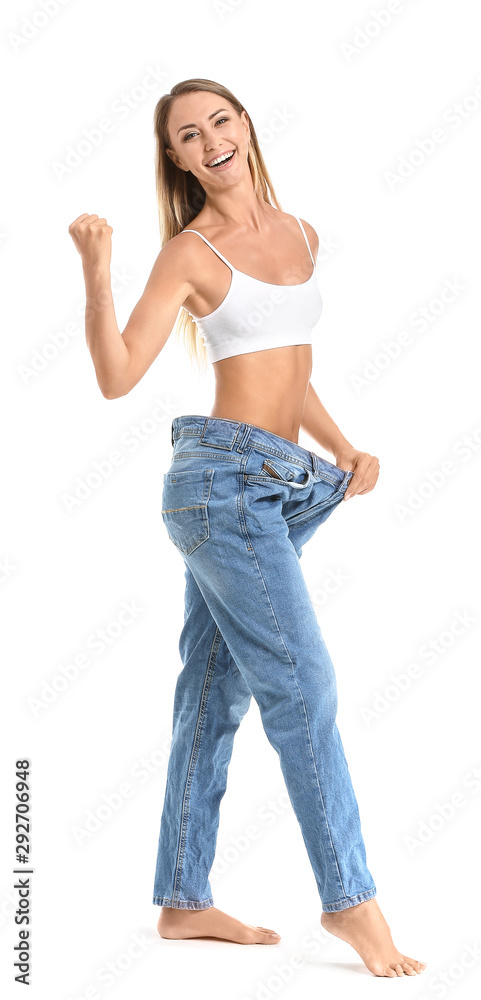 Happy young woman in loose jeans on white background. Weight loss concept