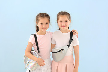 Wall Mural - Portrait of cute twin girls with stylish bags on color background