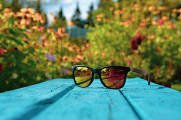 sunglasses on a floral background with a blue bench