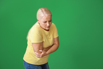 Sticker - Mature woman suffering from pain in elbow on color background