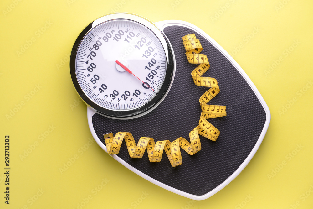 Scales and measuring tape on color background. Weight loss concept
