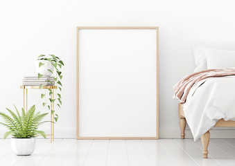 Poster mockup with vertical wooden frame standing on floor in bedroom interior with unmade bed, pink plaid and green plants on empty white wall background. 3D rendering, illustration.