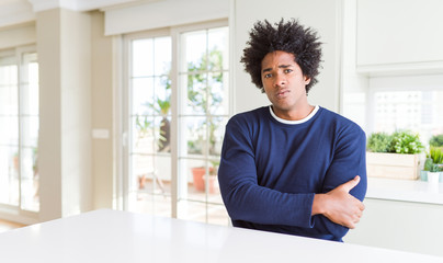 Sticker - Young african american man wearing casual sweater sitting at home skeptic and nervous, disapproving expression on face with crossed arms. Negative person.