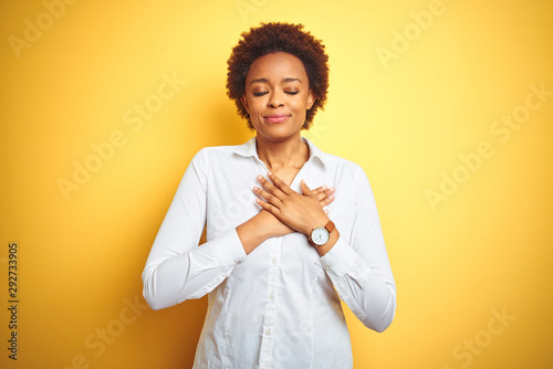 African american business woman over isolated yellow background smiling with hands on chest with closed eyes and grateful gesture on face Tableau sur Toile