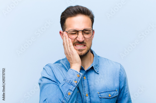 Fotografía young handsome man holding cheek and suffering painful toothache, feeling ill, m