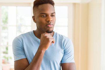 Canvas Print - Handsome young african man thinking and questioning with pensive face, hand on chin wondering about a doubt