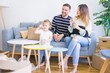© Krakenimages.com - Beautiful family, parents sitting on the sofa drinking coffee looking his kid playing at new home around cardboard boxes