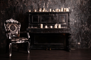 old black vintage piano with white candles and retro chair. nobody