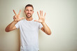 © Krakenimages.com - Young handsome man wearing casual white t-shirt over isolated background showing and pointing up with fingers number eight while smiling confident and happy.