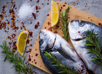 Raw fish cooking and ingredients. Dorado, lemon, salt, herbs and spices. Top view on table