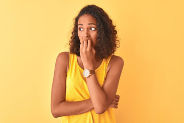 Poster - Young brazilian woman wearing t-shirt standing over isolated yellow background looking stressed and nervous with hands on mouth biting nails. Anxiety problem.