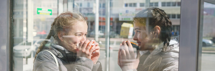 smiling young teen girlfriends drinking coffee or tea and gossiping outdoors, people, communication 