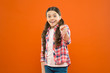 © be free - wow. little girl orange background. kid fashion. smiling school girl point finger. worker uniform. kid long hair. small girl checkered shirt. happy child. happy childrens day. childhood happiness