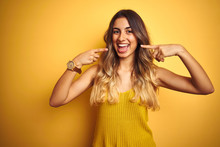 Young Beautiful Woman Wearing T-shirt Over Yellow Isolated Background Smiling Cheerful Showing And Pointing With Fingers Teeth And Mouth. Dental Health Concept.