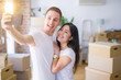 © Krakenimages.com - Young beautiful couple standing using smartphone to take a selfie at new home around cardboard boxes