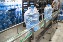 Conveyor Line Or Belt With Clean Pure Drinking Water In Plastic Bottles Packed In Cellophane, Loading Finished Goods At Water Factory