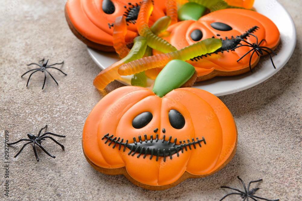 Plate with creative cookies for Halloween celebration on grey background
